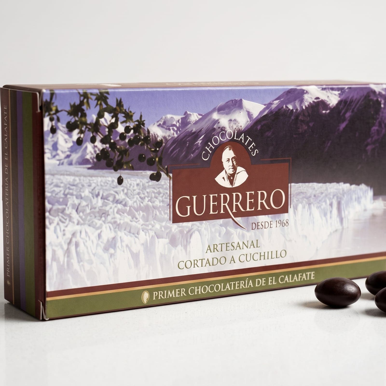 Caja cerrada del surtido de chocolates artesanales de 1/2 kg, con el Glaciar Perito Moreno en la tapa y la leyenda "artesanal, cortado a cuchillo"