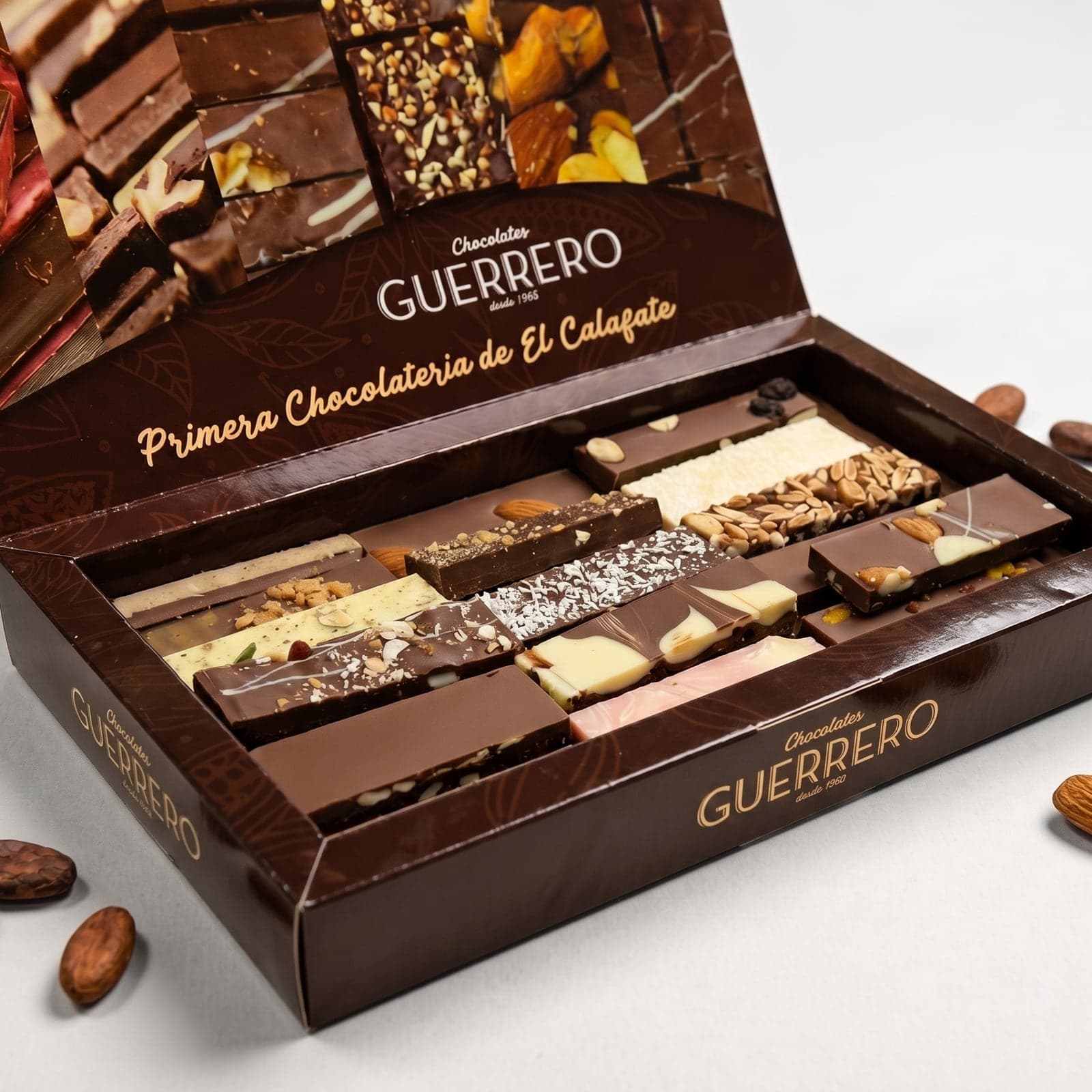 Caja abierta del surtido de chocolates artesanales de 1 kg, con almendras al costado y la tapa que dice "Primera Chocolatería de El Calafate"